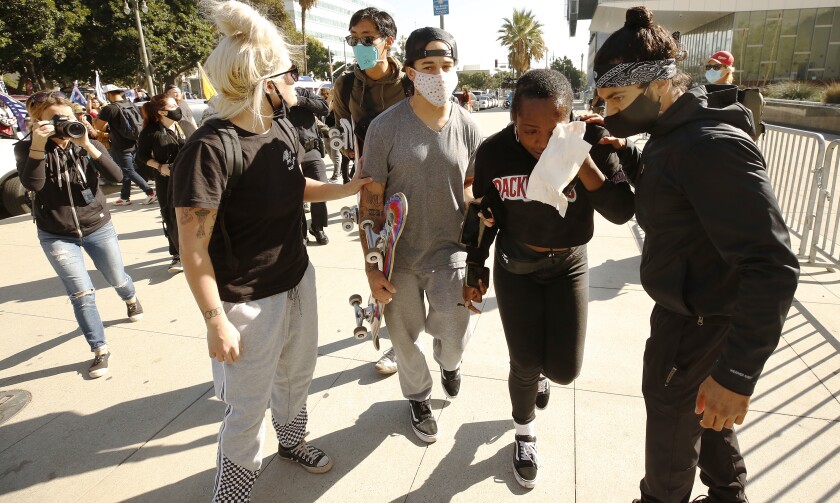 Berlinda Nibo is escorted from a crowd of pro-Trump demonstrators in Los Angeles.