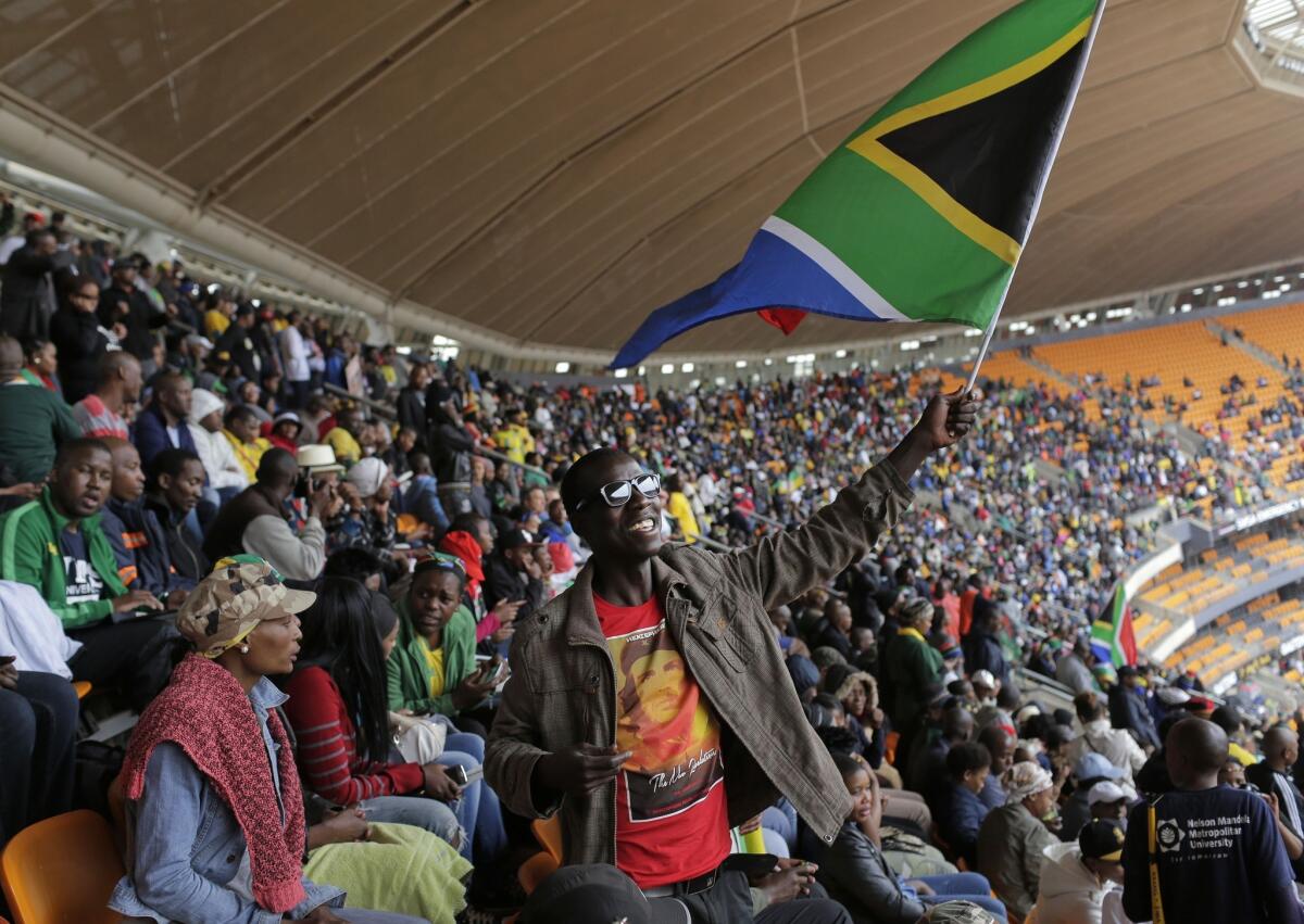 A man waves a South African flag as he arrives for the memorial service for former South African President Nelson Mandela at a stadium in Soweto.