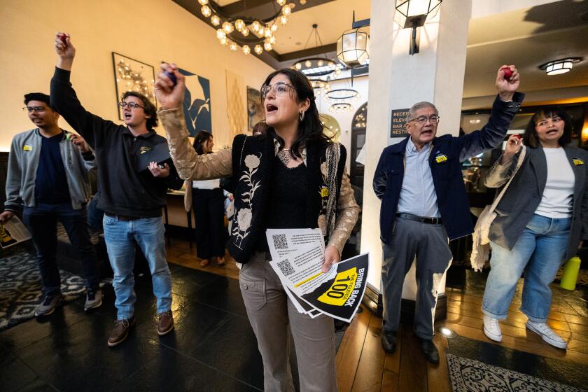 Los Angeles, CA - March 01: Isabela Piedrahita, center, shouts "Bring them back" as she joins dozens of demonstrators participating in a "water-in" at the Cafe Fig restaurant in support of more than a hundred workers who lost their jobs when the Hotel Figueroa's owner and its new operator failed to retain the workers when the new operator took over on Friday, March 1, 2024 in Los Angeles, CA. (Brian van der Brug / Los Angeles Times)