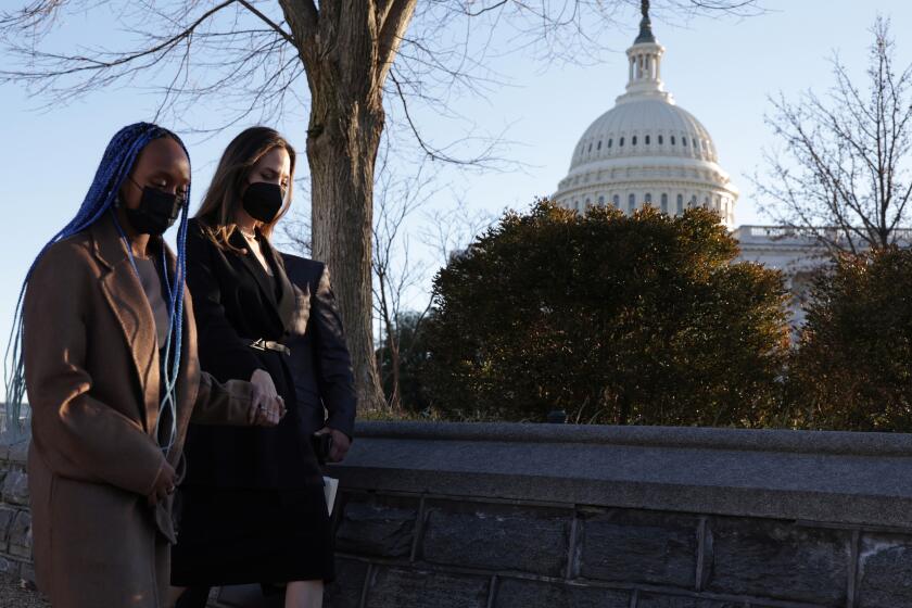 Two women in masks walk outdoors with the U.S. Capitol in the background