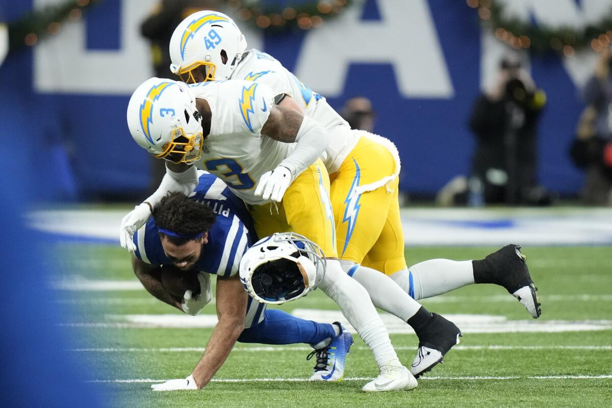 The Colts' Michael Pittman Jr. loses his helmet as he is tackled by Chargers Derwin James Jr. (3) and Drue Tranquill.