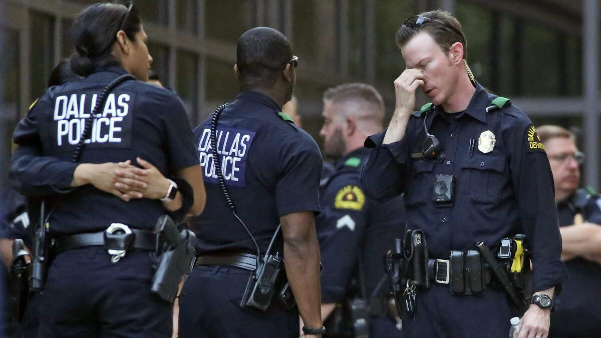 Dallas police officers wait outside the entrance of the emergency room at Texas Health Presbyterian Hospital Dallas following an April 24 shooting in which two officers were critically wounded.