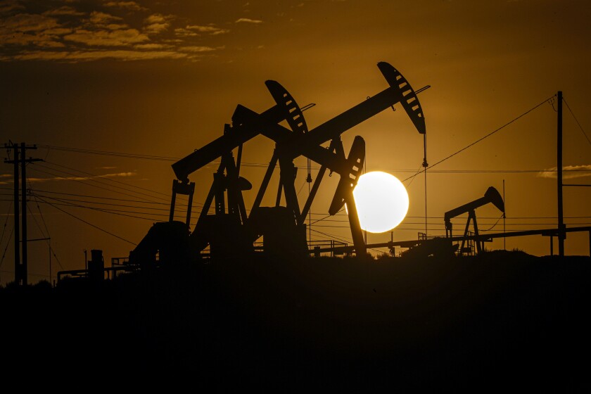 A setting sun silhouettes oil pumpjacks 
