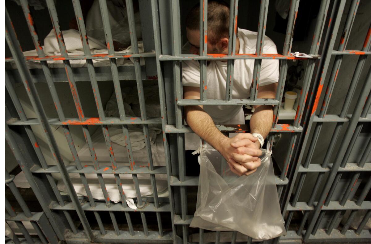 An inmate leans out the bars of his cell.