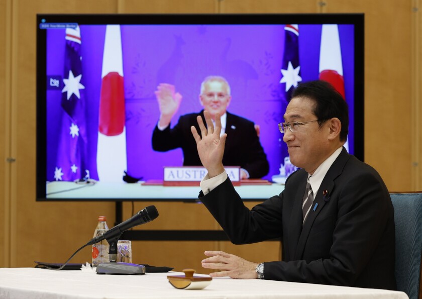 Japan's Prime Minister Fumio Kishida, right, and Australia's Prime Minister Scott Morrison seen on screen, attend a virtual summit to sign the Reciprocal Access Agreement, at Kishida's official residence in Tokyo, Japan Thursday, Jan. 6, 2022. The leaders of Japan and Australia signed a “landmark” defense agreement Thursday that allows closer cooperation between their militaries and stands as a rebuke to China's growing assertiveness in the Indo-Pacific region. (Issei Kato/Pool Photo via AP)