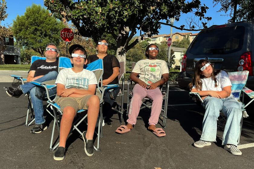 Azusa, California-Oct. 14, 2023-An Azusa family watches the eclipse from the parking lot of the Rosedale community center. (Robert Gauthier/Los Angeles Times)