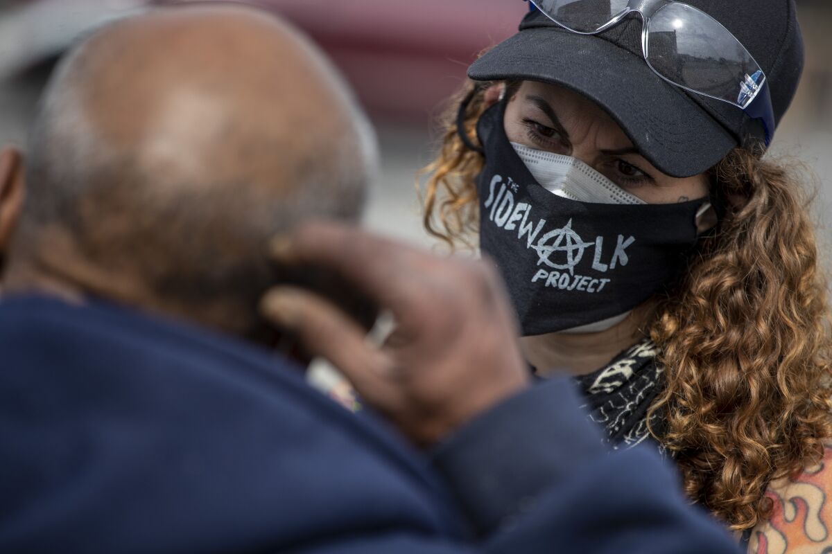 Soma Snakeoil wears a Sidewalk Project face mask while taking to a man on L.A.'s skid row.