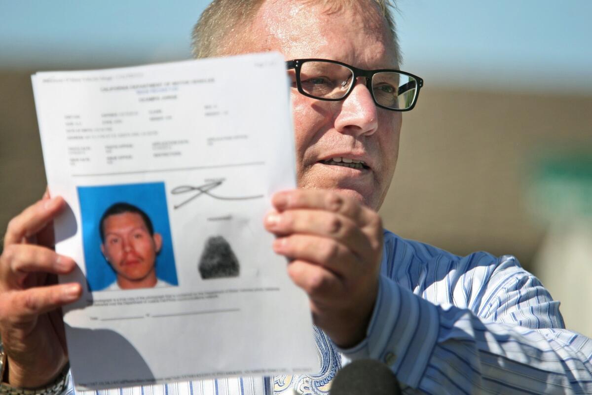 Cpl. Anthony Bertagna of the Santa Ana police holds a picture of Jorge Ocampo, the suspect in fatal traffic collision.