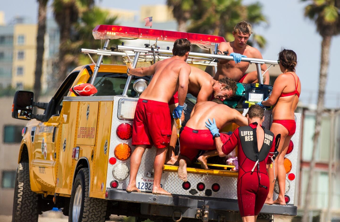 Lifeguards assist a person who was in the water and apparently struck by lightning at Venice Beach on Sunday.