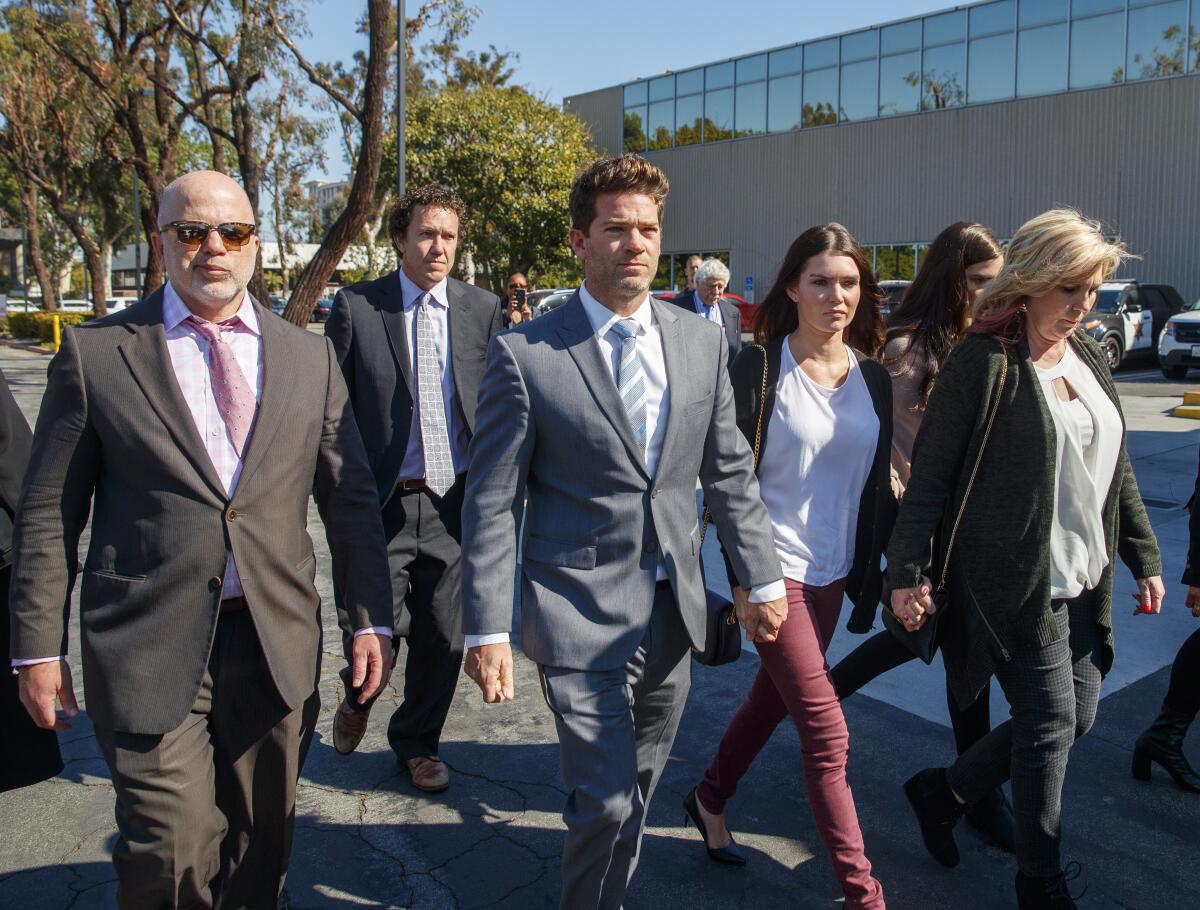 Defense attorney Philip Kent Cohen, left, and clients Dr. Grant Robicheaux, center, and Cerissa Riley, third from right, leave the Harbor Justice Center on Friday in Newport Beach after Orange County Superior Court Judge Gregory Jones delayed a ruling on dismissing rape charges against the doctor and his girlfriend, saying politics had "infected this case."