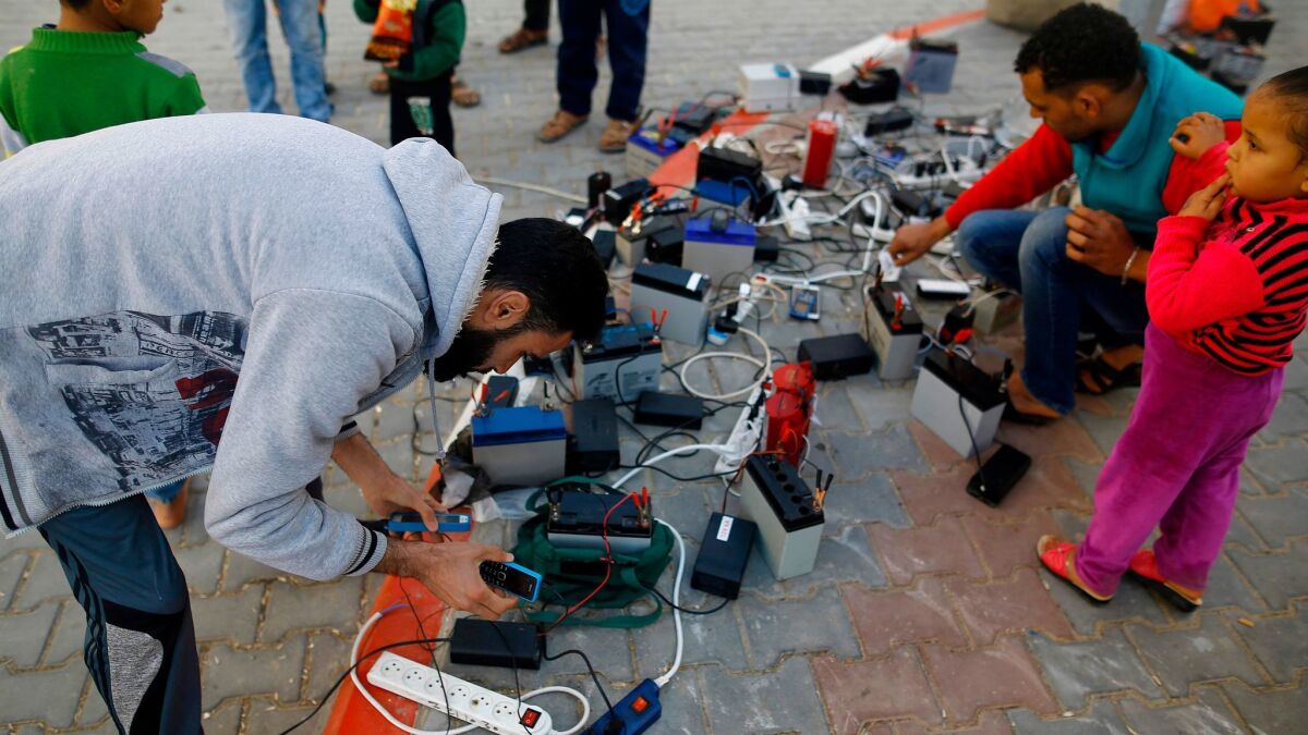 Palestinian charge their cellphones using batteries, a free service offered in a Gaza City neighborhood suffering from power disruptions.