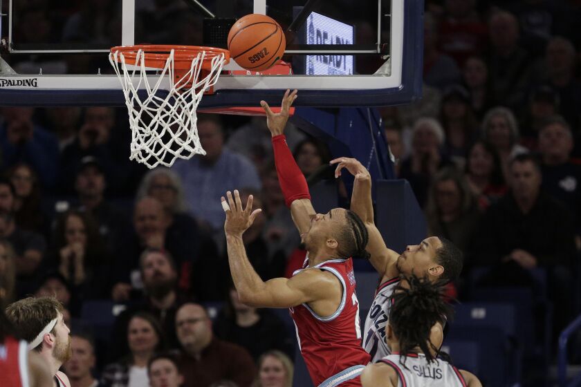 Loyola Marymount guard Cam Shelton, center, shoots while defended by Gonzaga guard Nolan Hickman, right, during the second half of an NCAA college basketball game, Thursday, Jan. 19, 2023, in Spokane, Wash. Loyola Marymount won 68-67. (AP Photo/Young Kwak)