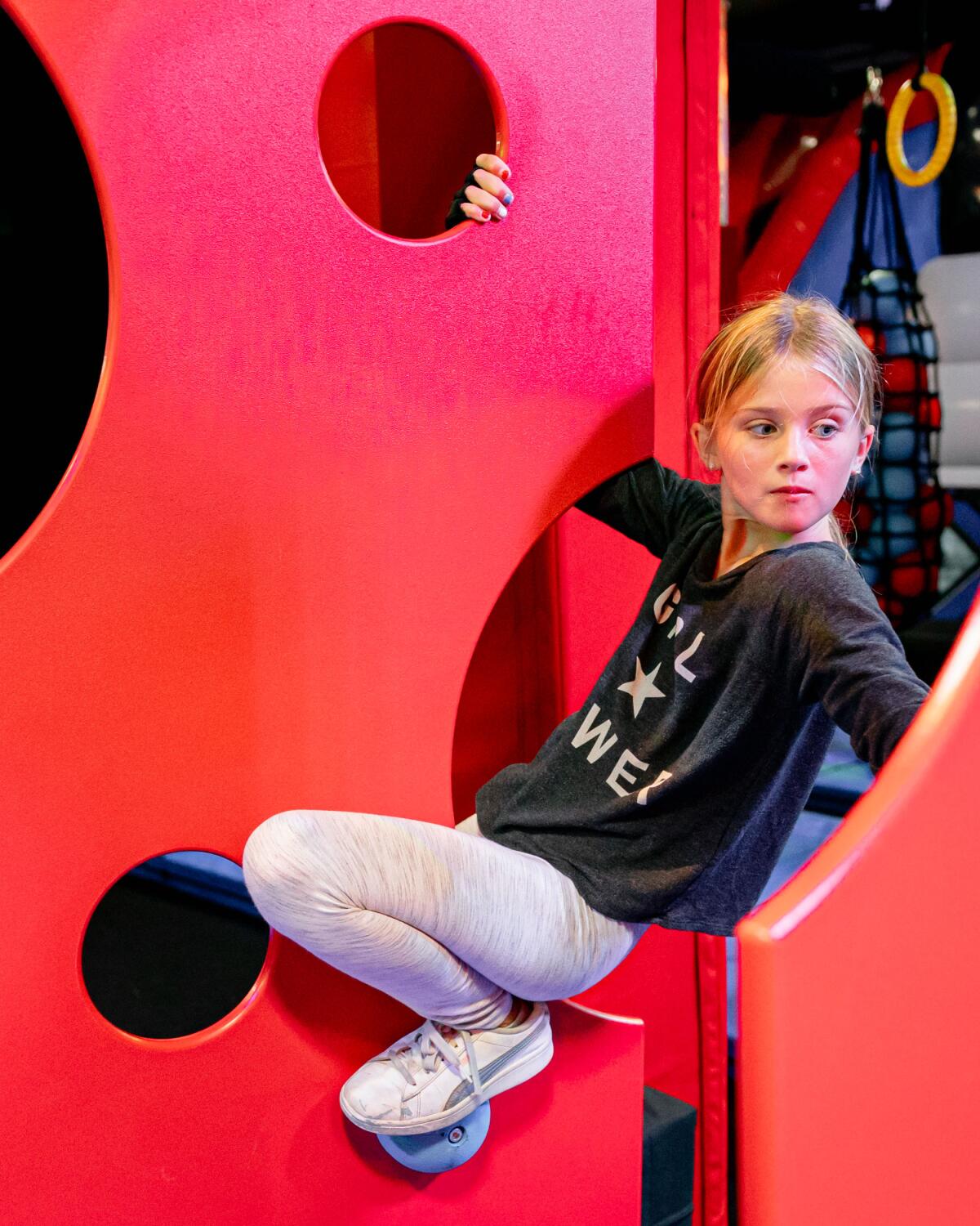 A girl climbs between rock climbing walls.