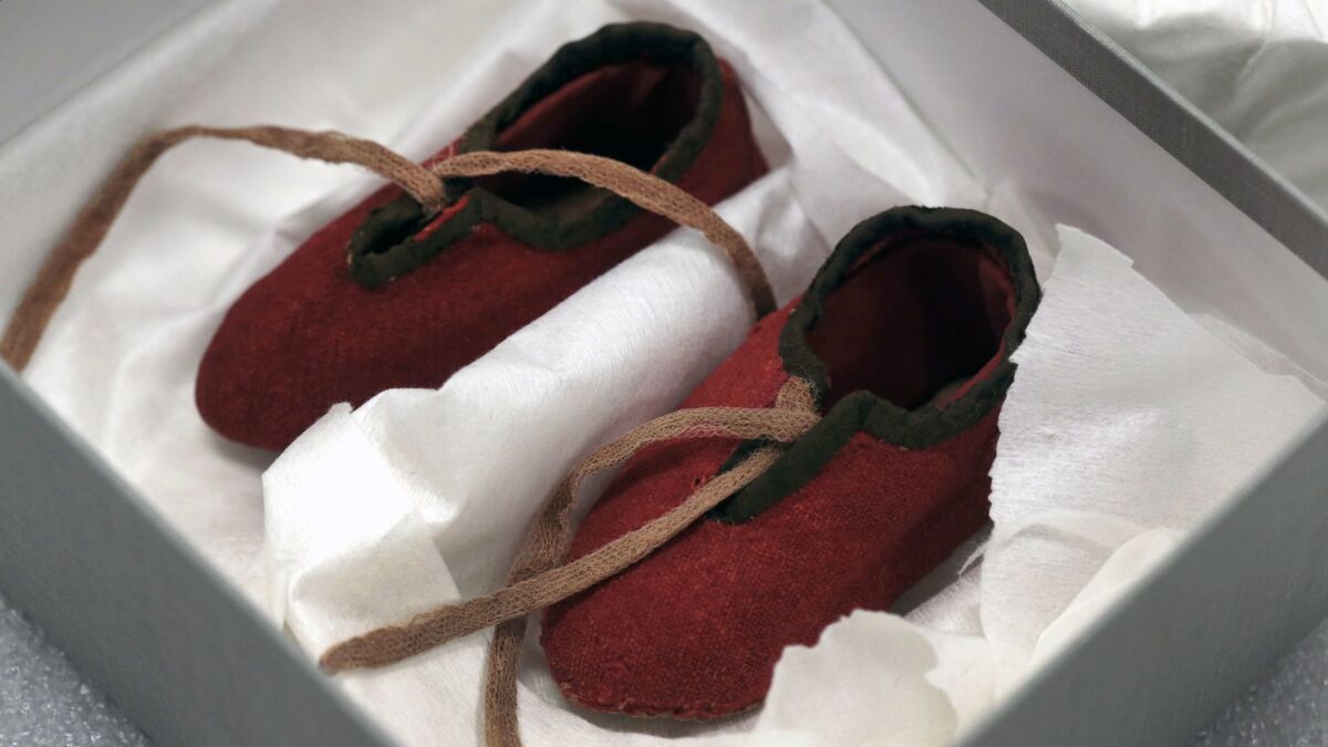 Baby booties from the 1780s, made from a British red coat, are displayed in a storage box at the museum.