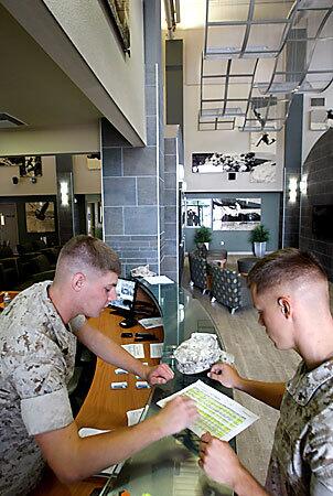 Marine Cpl. Michael Breight, left, helps Pfc. Joseph Blatter with his room assignment in the new bachelor enlisted barracks at Camp Pendleton. The reception area features a curved glass counter, 30-foot ceilings and super-graphics on the walls.