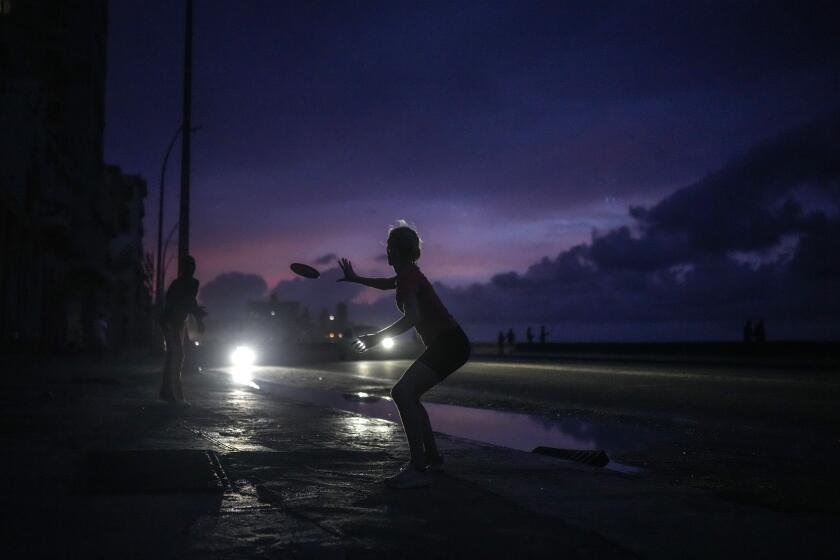 Una mujer se prepara para agarrar un frisbee durante el apagón masivo en el que derivó la caída en el funcionamiento de una de las mayores plantas termoeléctricas del país, en La Habana, Cuba, el viernes 18 de octubre de 2024. (AP Foto/Ramón Espinosa)