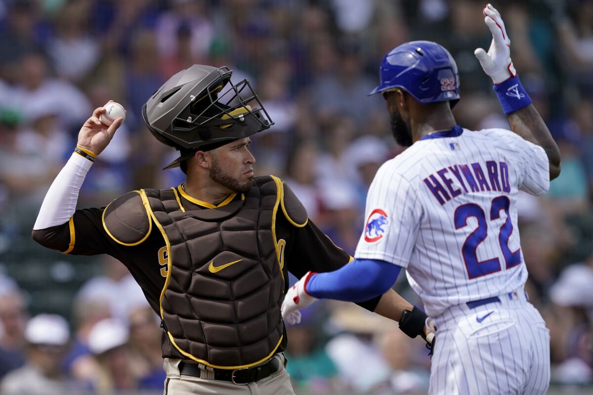 Chicago Cubs' Jason Hayward playfully interferes with the throw of San Diego Padres catcher Victor Caratini after Haward flew-out to left field during the first inning of a spring training baseball game, Saturday, March 19, 2022, in Mesa, Ariz. (AP Photo/Matt York)