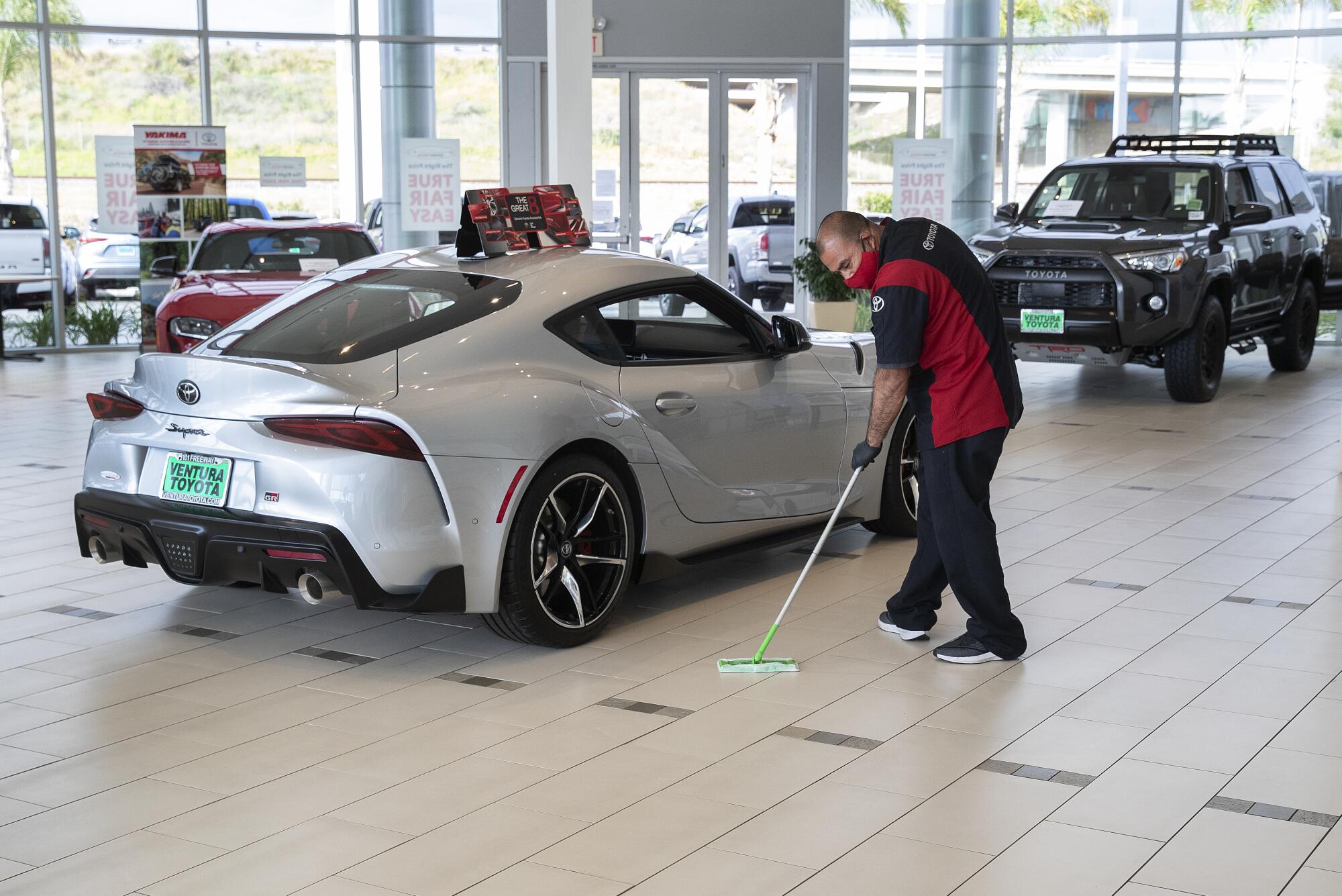 Gustavo Gutierrez mops the showroom floor with disinfectant at reopened Ventura Toyota.