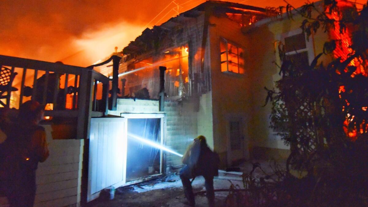 In this July 6 photo provided by the Santa Barbara County Fire Department, firefighters put water on flames at a Goleta home. With the Holiday fire 85% contained, one resident, John Davis, returned to find his house (not pictured) was still standing.