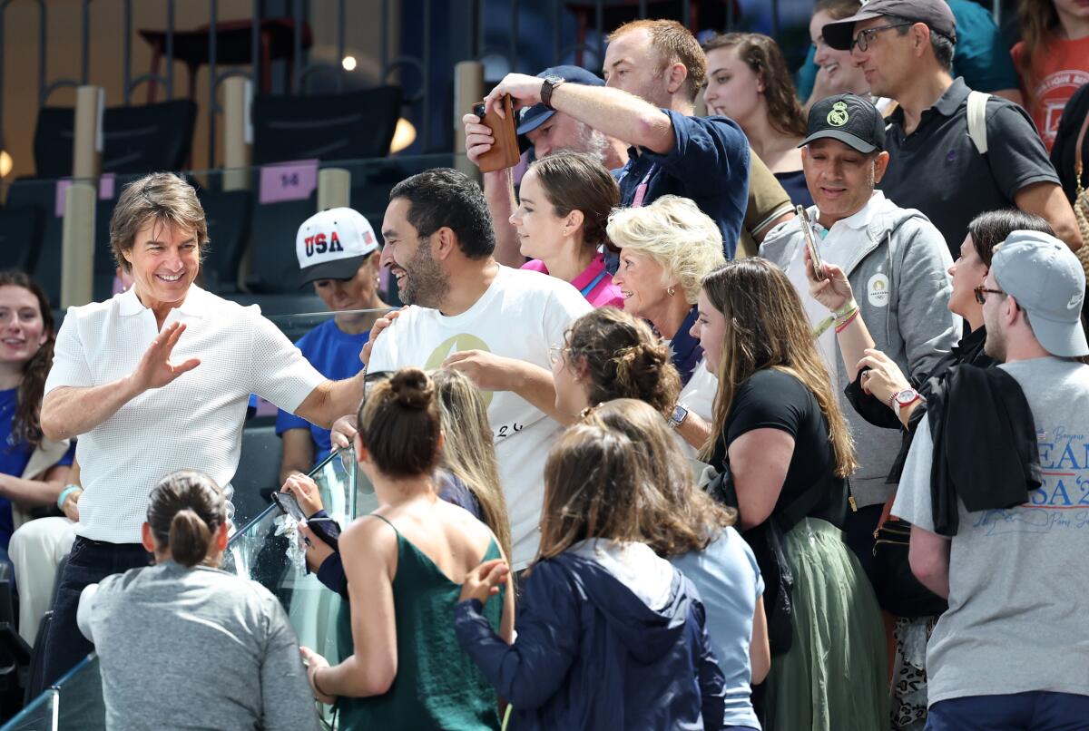 Tom Cruise, left, greets fans before women's team gymnastics qualifications on Sunday.