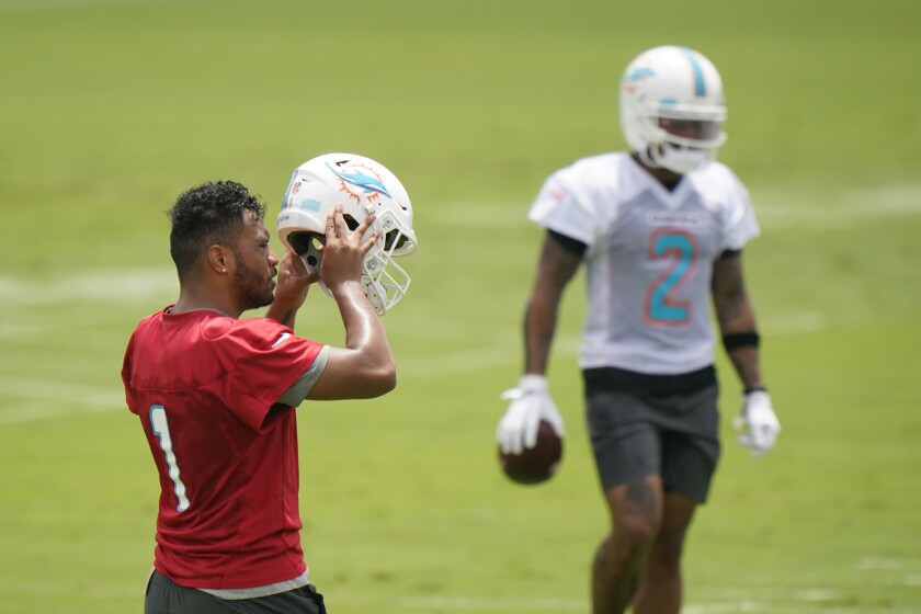 Miami Dolphins quarterback Tua Tagovailoa (1) takes off his helmet between drills during a mandatory minicamp at the NFL football team's training camp, Tuesday, June 15, 2021, in Davie, Fla. (AP Photo/Wilfredo Lee)