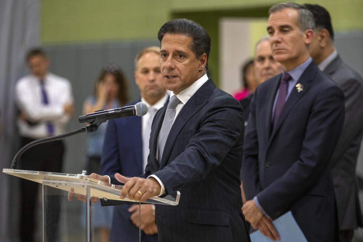 A man stands at a lectern while other people stand behind him.