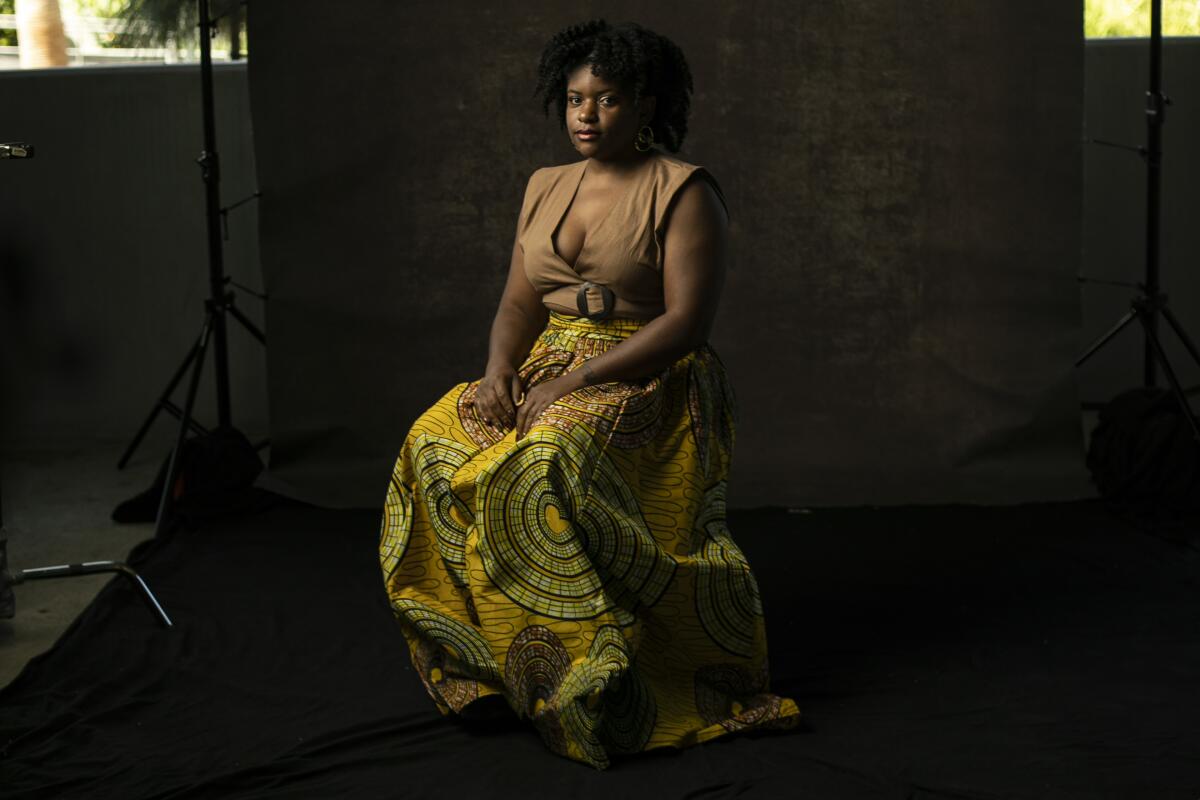 A woman in a long, African-print skirt poses for a portrait. 