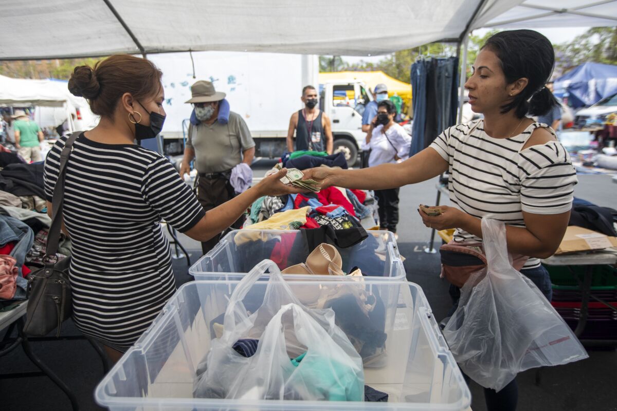 One woman buys clothing from another at the Los Angeles City College swap meet.