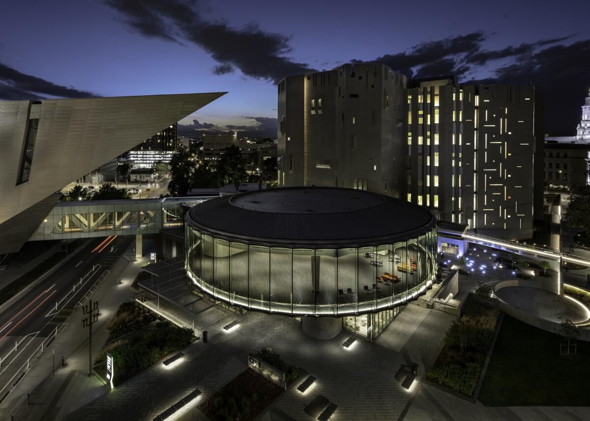 A view from on high of a circular building with glass walls and adjacent structures.