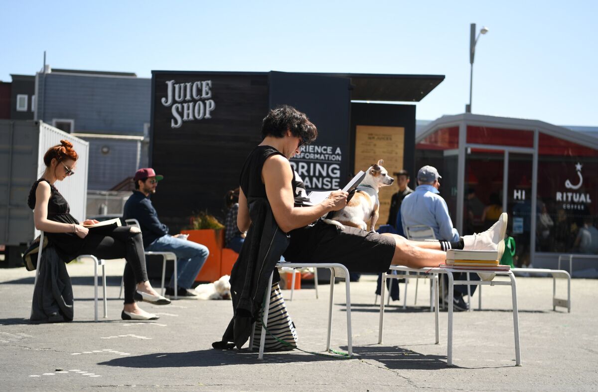 People relax outside during a spring day in the Hayes Valley area of San Francisco.