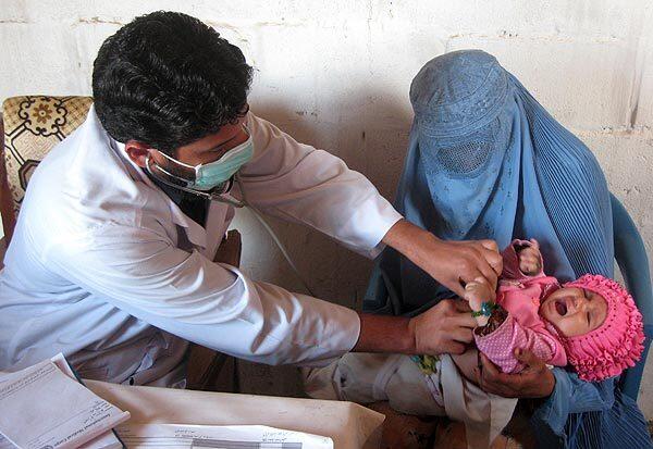 Dr. Sahib Zada Zalmay checks an infant at the International Medical Corps health center at Lower Sheikh Mesri camp for returning refugees near Jalalabad, Afghanistan. The girl's mother, Hayat Bibi, said she had been coughing. "It is very good that I help my people," Zalmay said.