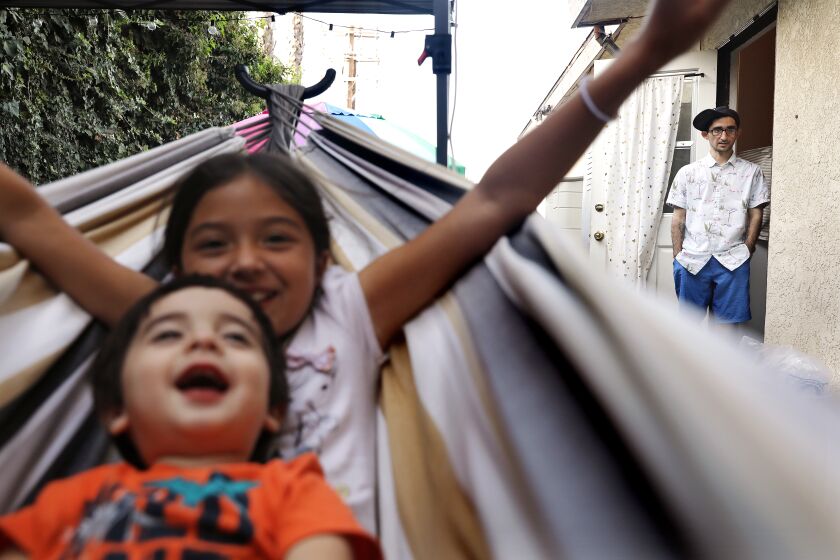 Tovi Baskin, front, and Lillian Mazzucca play in a hammock during a family bbq to celebrate their uncle Anthony's 31st birthday, as Anthony Mazzucca, at right, looks on, on Tuesday, April 5, 2022. (Christina House / Los Angeles Times)