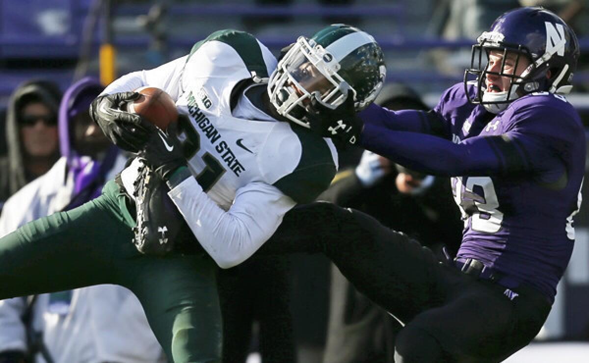 Michigan State cornerback Darqueze Dennard is facemasked by Northwestern wide receiver Mike McHugh while intercepting a pass during a Nov. 23 game. Dennard has proven to be a very valuable asset to the Spartans' secondary.