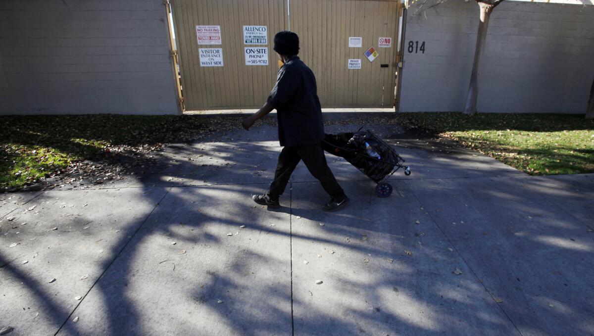 A person walks past the gate of a South L.A. facility operated by AllenCo Energy Co. in this 2013 file photo. AllenCo has suspended operations at the site for the past five years.