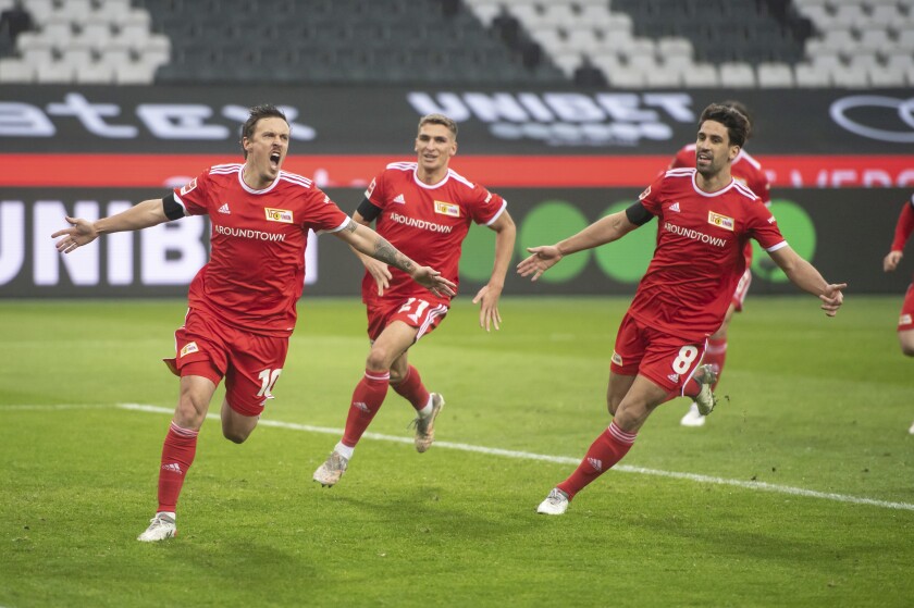 Union Berlin's Max Kruse, left, cheers with Union Berlin's Robin Knoche and Union Berlin's Rani Khedira after he scored the opening goal during the Bundesliga soccer match between Borussia Moenchengladbach and 1. FC Union Berlin in Moenchengladbach, Germany, Saturday, Jan. 22, 2022. (Bernd Thissen/dpa via AP)