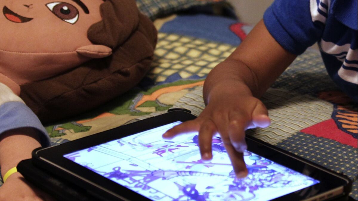 FILE - In this Friday, Oct. 21, 2011, file photo, a child plays with an iPad in his bedroom. Parents of small children have long been hearing about the perils of screen time. And with more screens, its only getting worse. But working, taking care of children and remembering to eat is exhausting. Parents need those minutes of quiet. So maybe its time to relax a little. (AP Photo/Gerald Herbert, File)