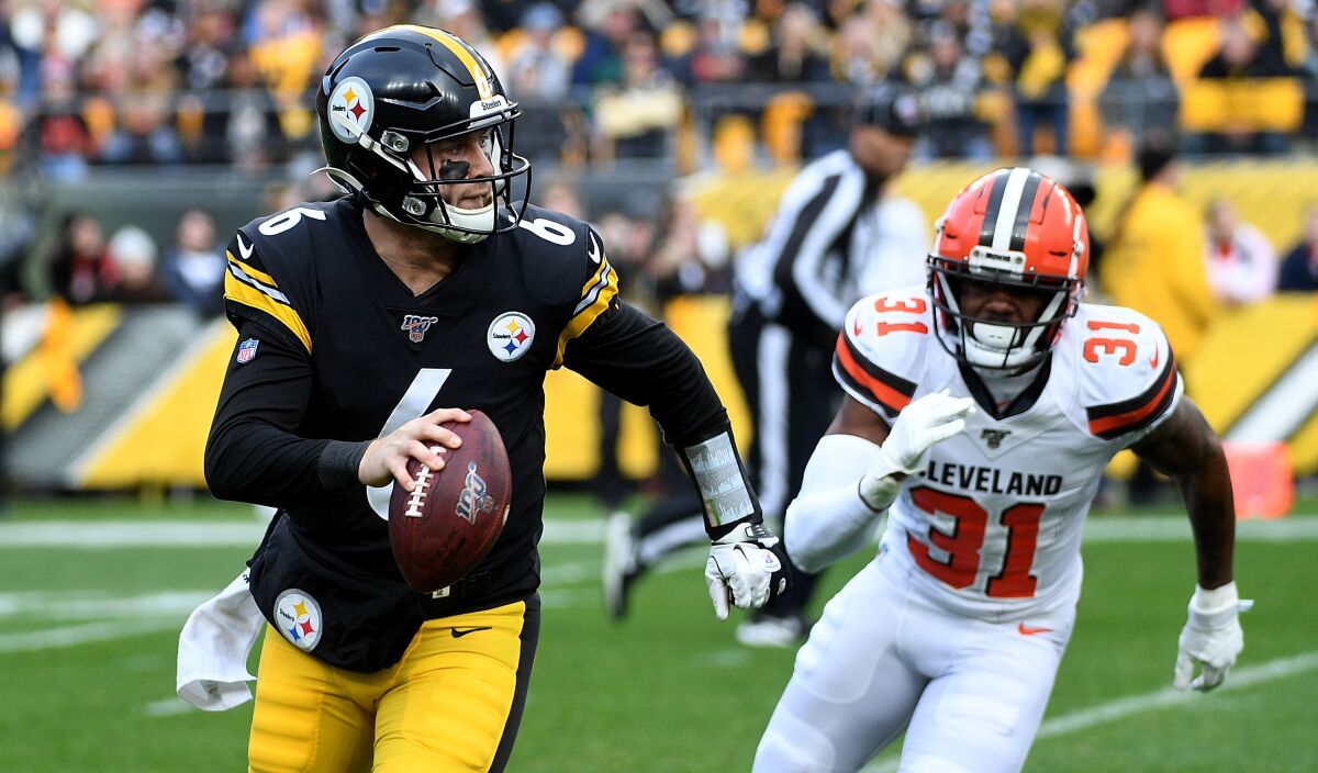 Pittsburgh Steelers quarterback Devlin Hodges scrambles out of the pocket under pressure from Cleveland safety Juston Burris.