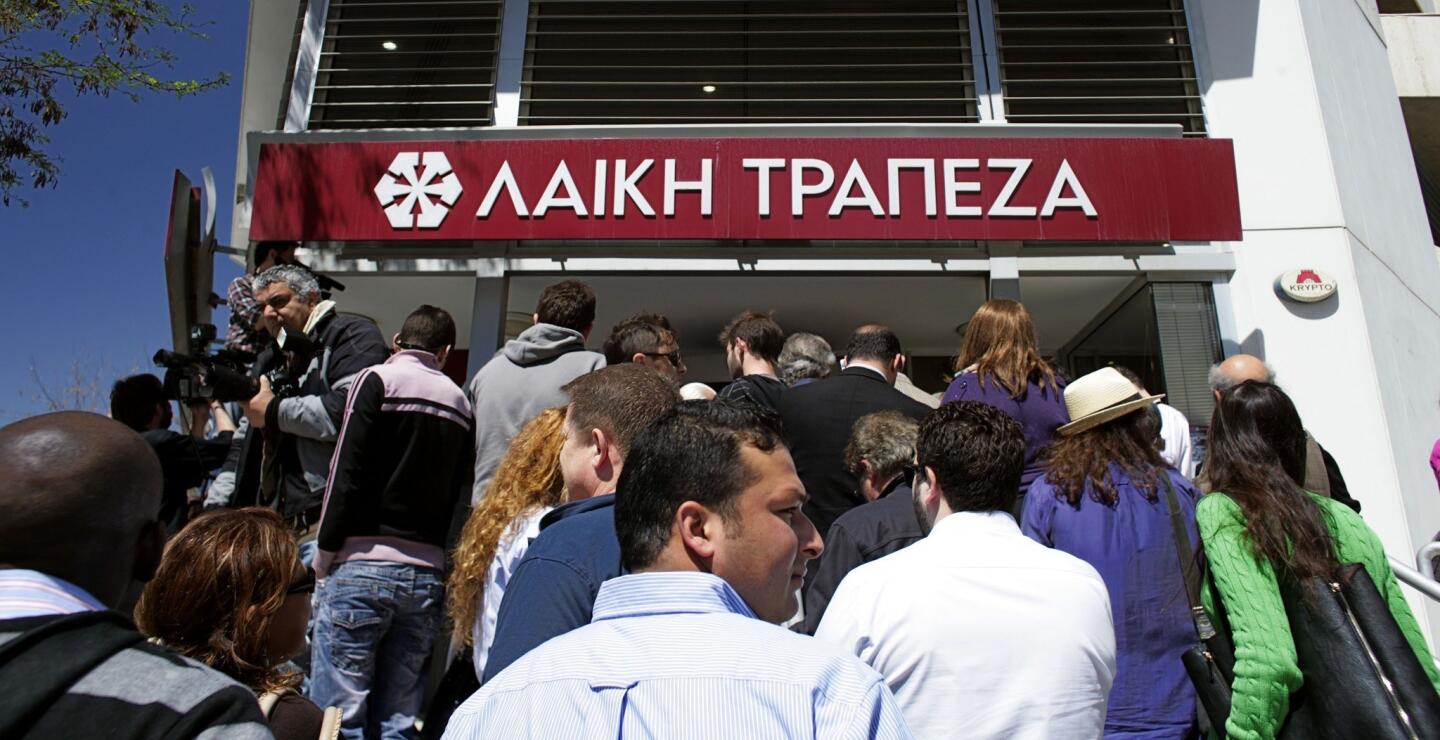 People gather in front of Laiki (Popula) Bank as the country's banks reopen following 12 days of closure in Nicosia.