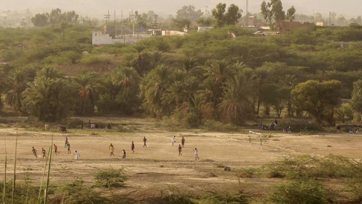 Children play a game of soccer in a field near Mir Ali.