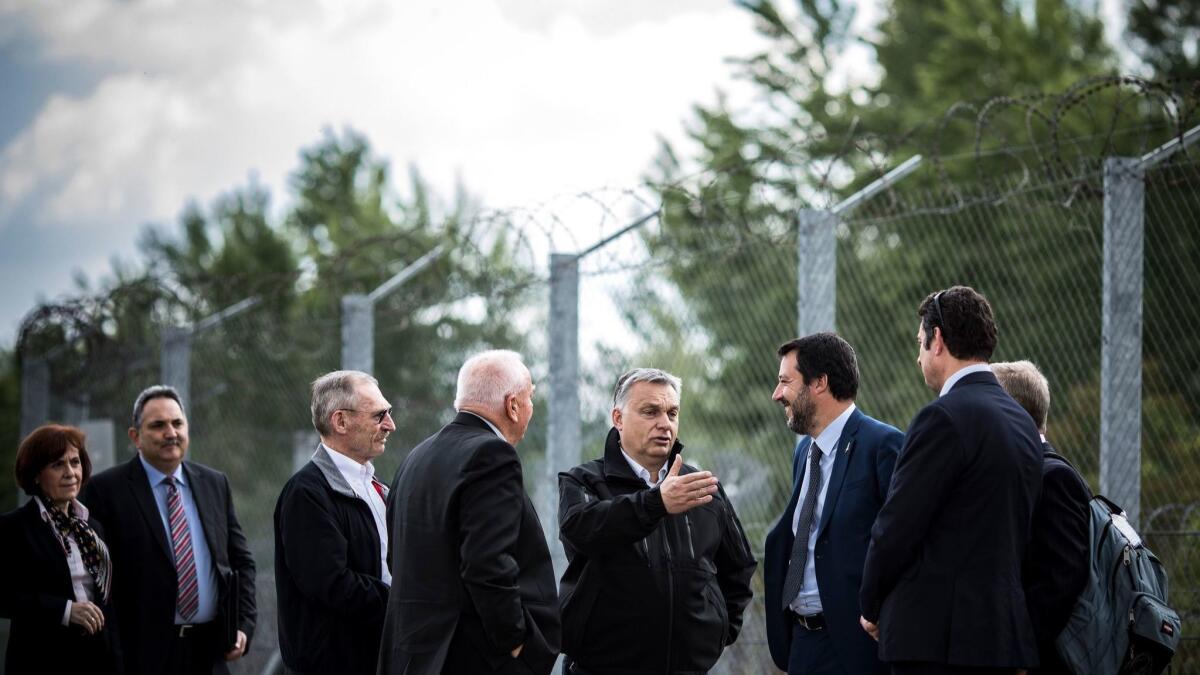A photo released by the Hungarian prime minister's press office shows Italian Deputy Premier and Interior Minister Matteo Salvini, second from right, talking with Hungarian Prime Minister Viktor Orban, third from right, May 2 along a fence on the Hungarian-Serbian border.