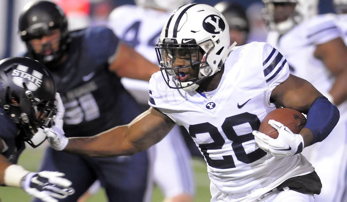 BYU running back Adam Hine, right, stiff-arms Utah State safety Marwin Evans during a game on Nov. 28.