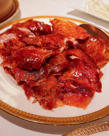 slices of Peking duck on a plate with a gold rim.