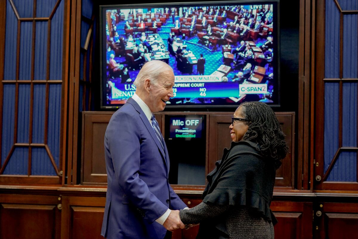 President Biden talks with Judge Ketanji Brown Jackson as they watch the Senate vote on her Supreme Court confirmation