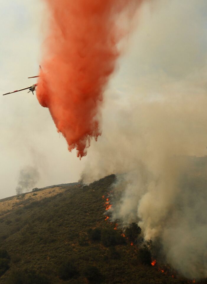 A fixed-wing aircraft drops a load of Phos-Chek on the Springs fire in the mountains above Malibu.