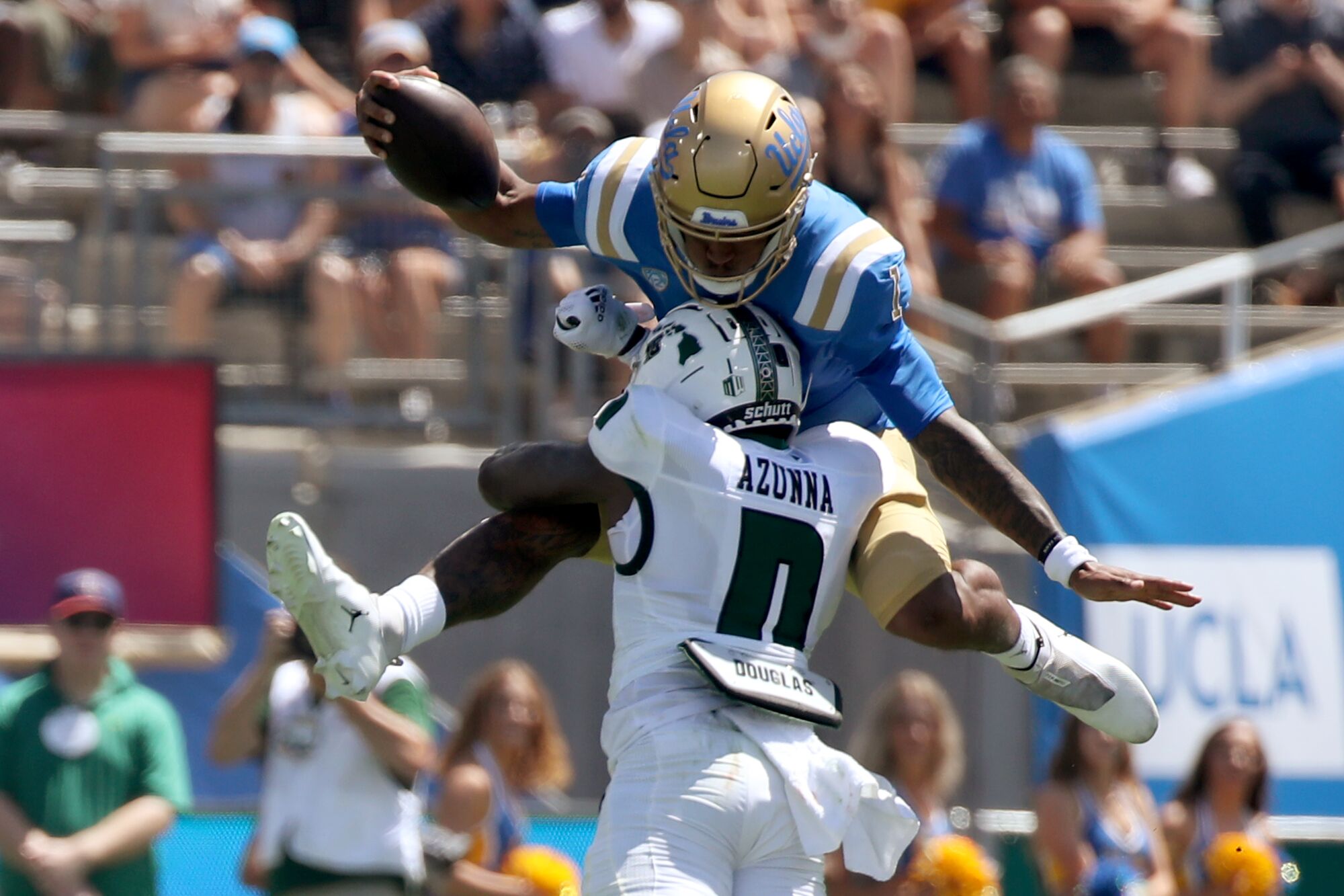 UCLA quarterback Dorian Thompson-Robinson tries to hurdle  Hawaii defender Chima Azonnah.