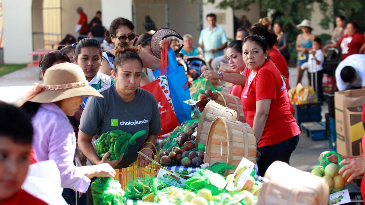 Families collect food from the Second Harvest Food Bank of Orange County's farmers market at Santa Ana High School recently.
