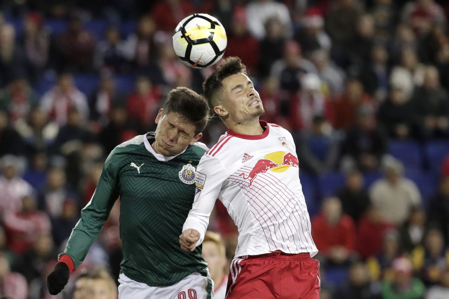 Guadalajara forward Jesus Godinez, left, and New York Red Bulls midfielder Florian Valot go up for the ball during the first half of the second leg of a CONCACAF Champions League soccer semifinal, Tuesday, April 10, 2018, in Harrison, N.J. (AP Photo/Julio Cortez)