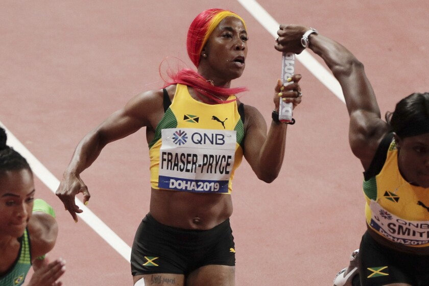 FILE - In this Friday, Oct. 4, 2019 file photo, Jamaica's Shelly-Ann Fraser-Pryce, center, hands off to Jonielle Smith, right, during a women's 4x100 meter relay semifinal at the World Athletics Championships in Doha, Qatar. On Friday, June 25, 2021, Fraser-Pryce cruised to a victory in the 100 meters at Jamaican national championships and will head to Tokyo in search of her third Olympic gold medal. (AP Photo/Nariman El-Mofty, File)