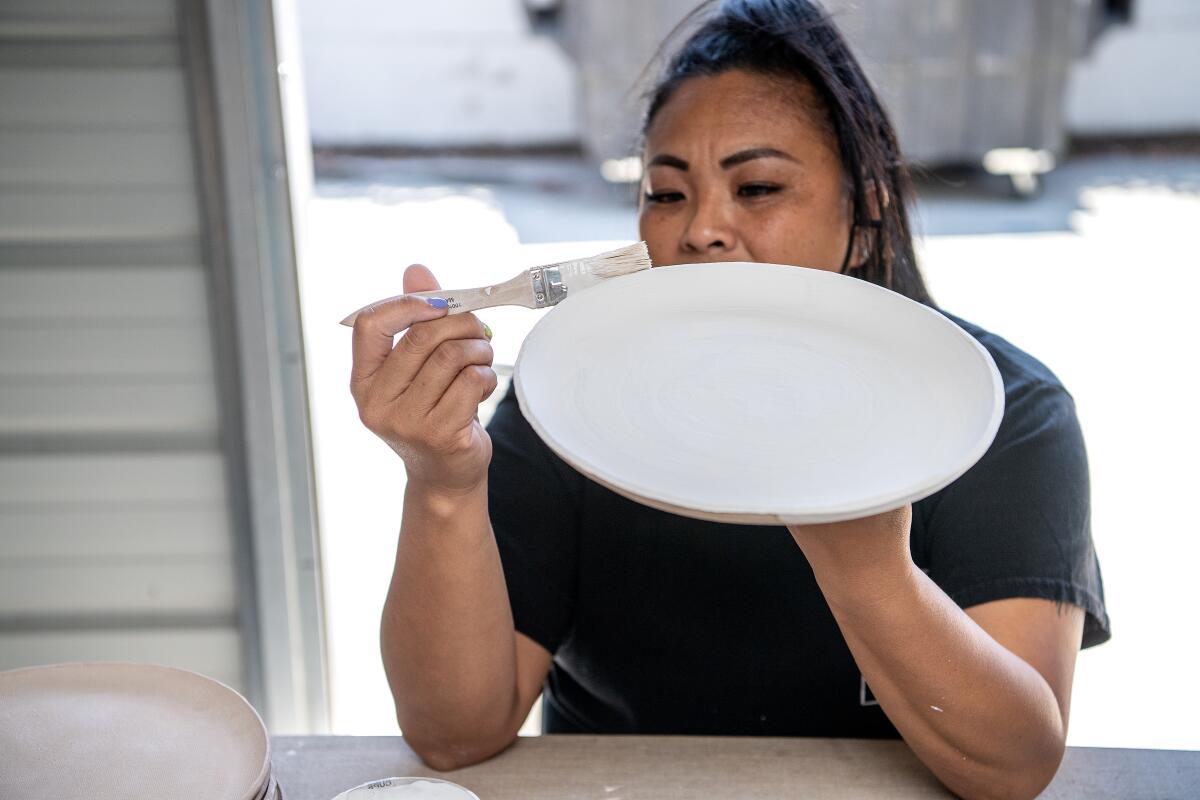 A woman works on a plate at a ceramics studio