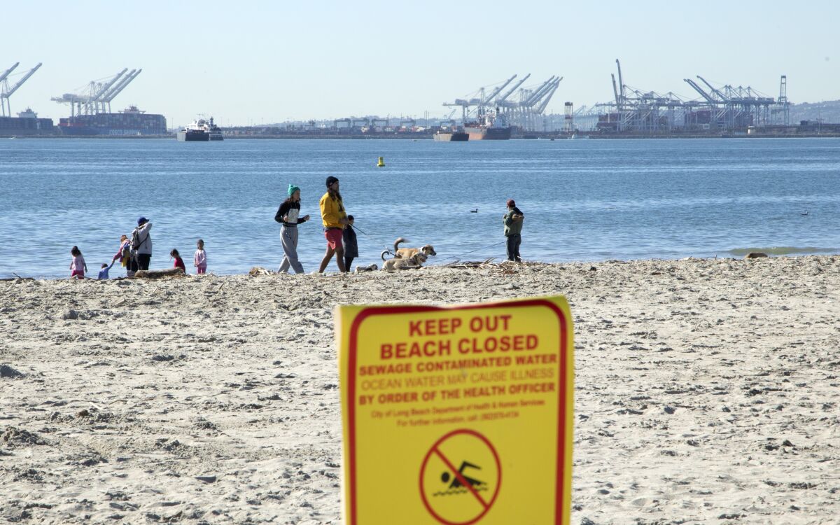 A sign warns beachgoers to stay out of the water because of sewage contamination